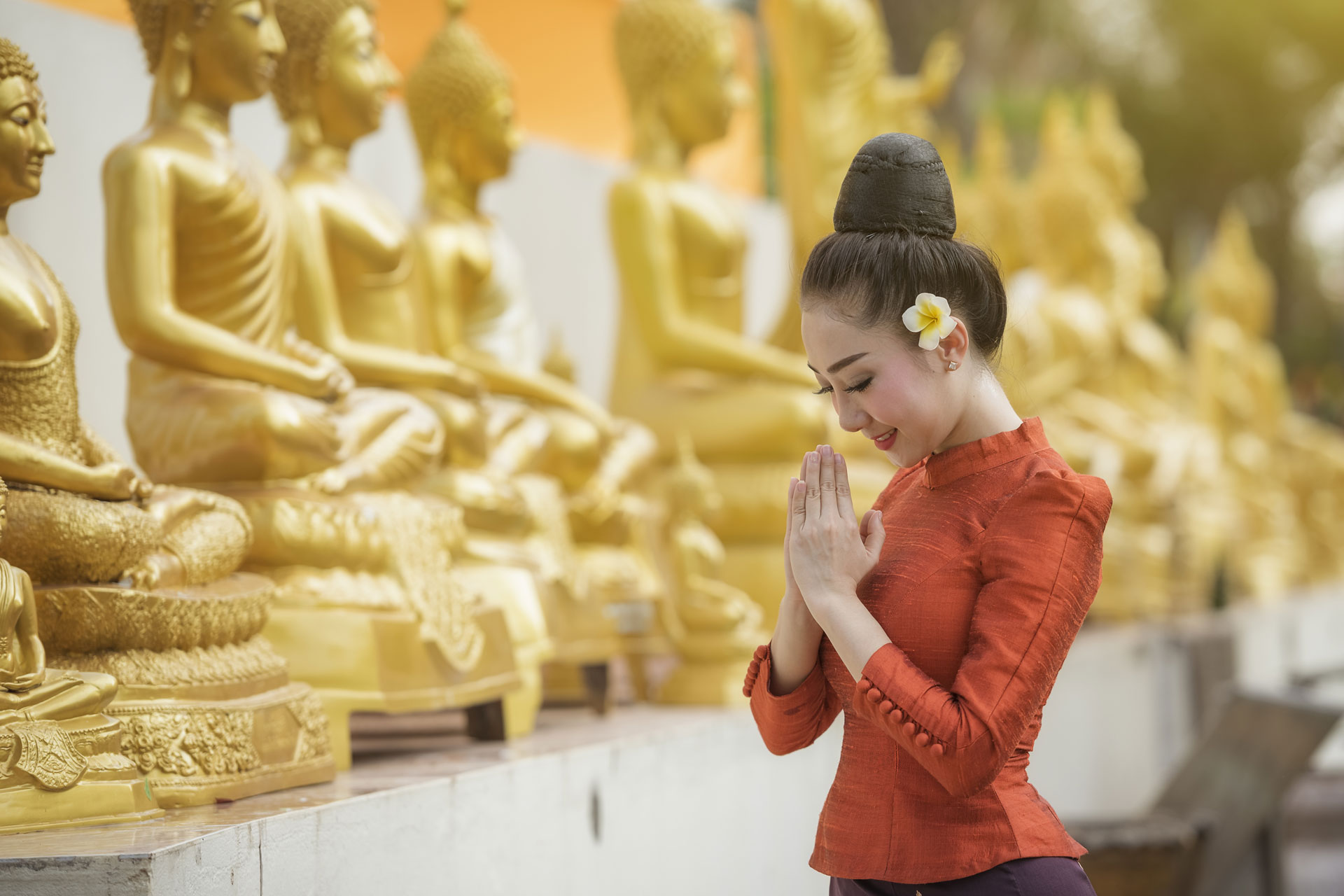 asian woman in front of many gold statues