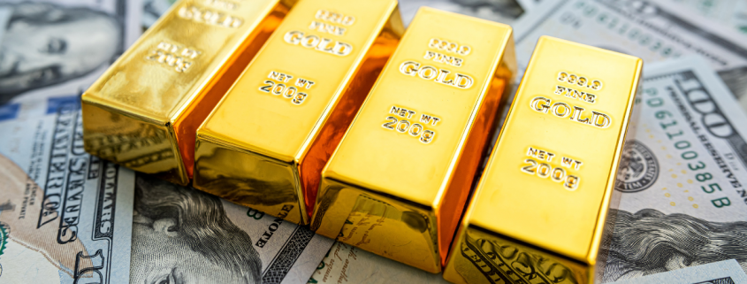 Is it Better to Own Cash or Gold? gold bars sitting on top of spread out $100 dollar bills