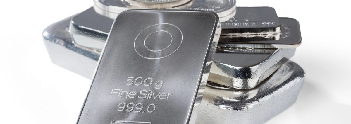 Is it Better to Own Stocks or Silver? - silver bars and coins stacked together on a white background