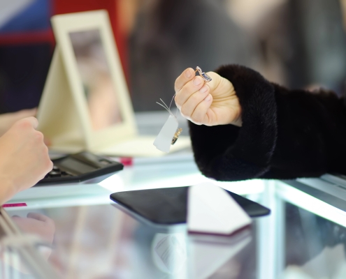 Woman choosing the perfect earrings at a jeweler, close up photo. Focus on your hands.