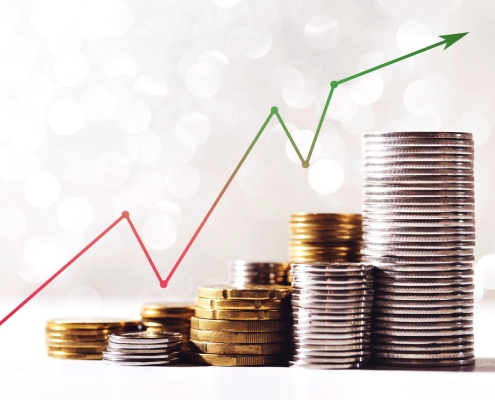 upward trending graph with gold and silver coins stacked below
